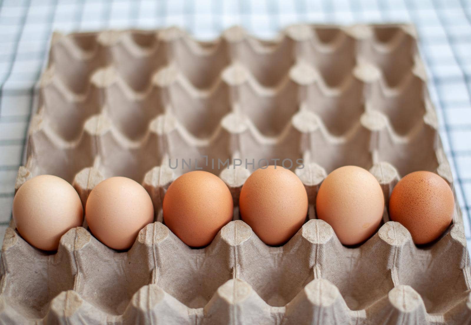 Several brown eggs lie in a row in a large cardboard bag, a chicken egg as a valuable nutritious product, a tray for carrying and storing fragile eggs