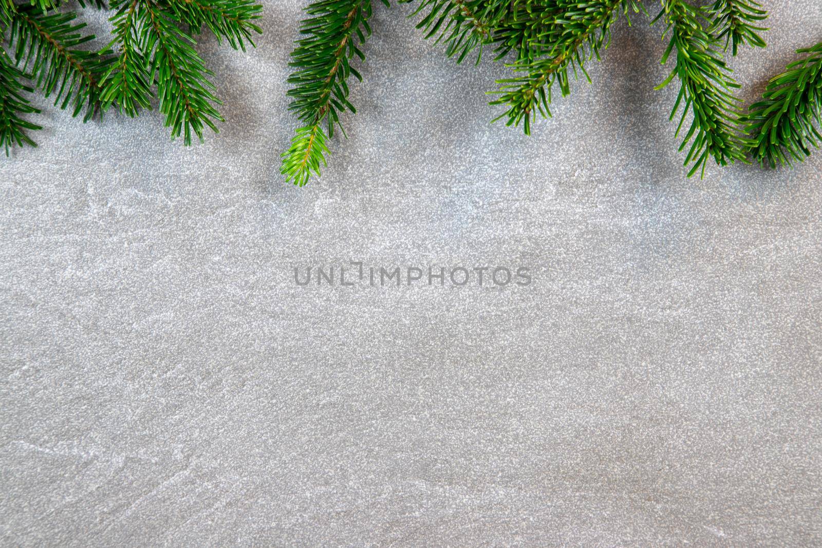 Christmas motif, texture, background with branches of a Nordmann fir at the top on a dark grey marbled  background with free space for text. by reinerc