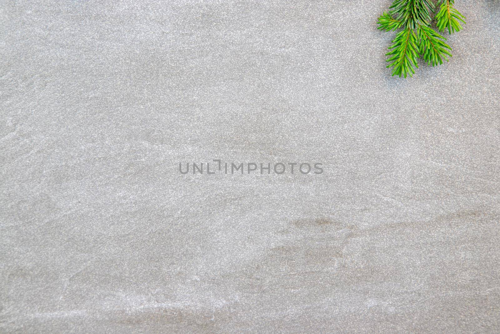 Christmas motif, texture, background with branches of a Nordmann fir right at the top on a grey marbled  background with free space for text
