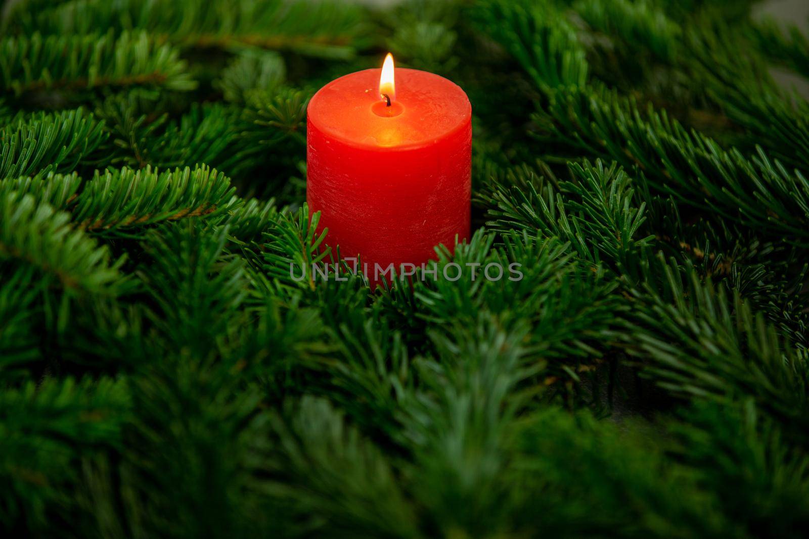 Christmas motif, texture, wallpaper, background with branches of a Nordmann fir and burning red candle on a grey marbled  background 