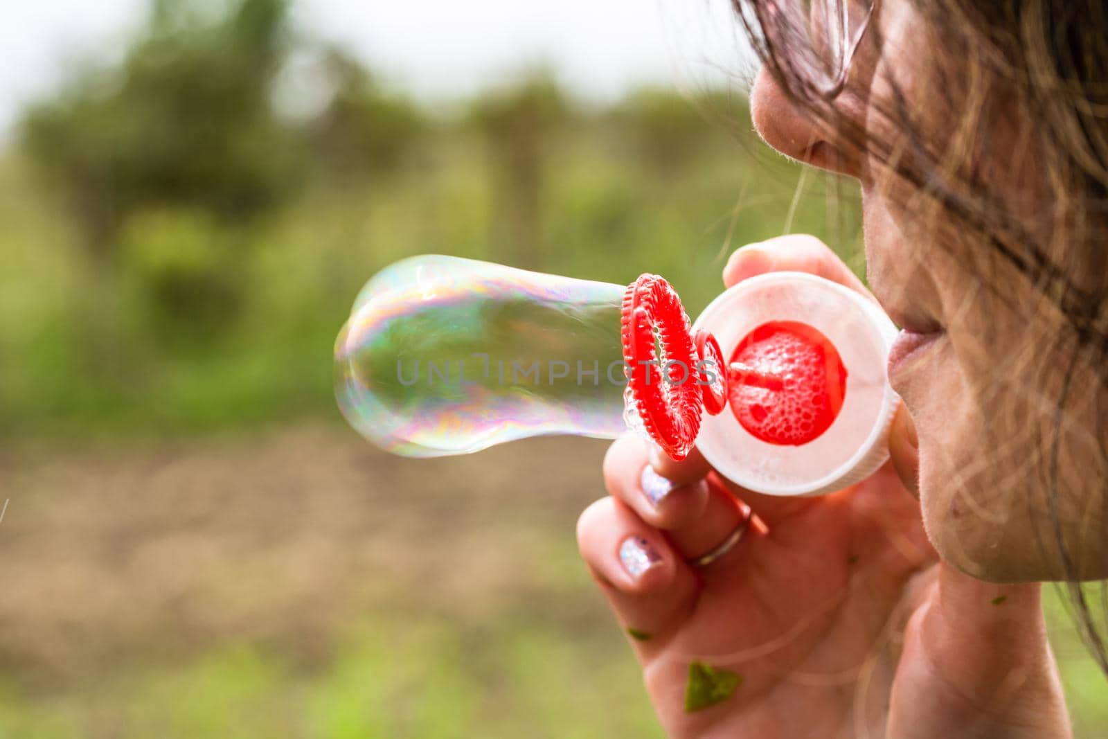 Close up photo of a girl blowing soap bubbles outdoor. by vladispas