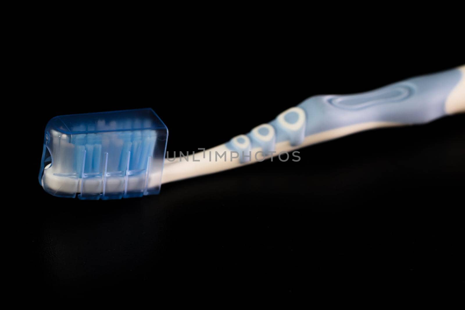 Selective focus on toothbrush isolated on black background.