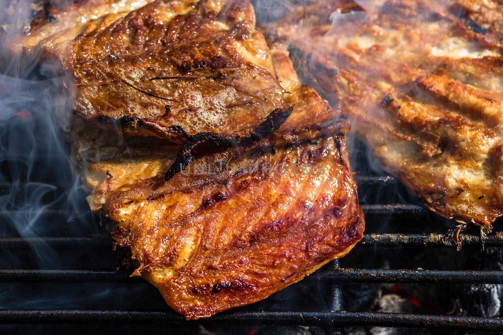 Grilled mackerel fish with smoke on a charcoal barbecue grill.