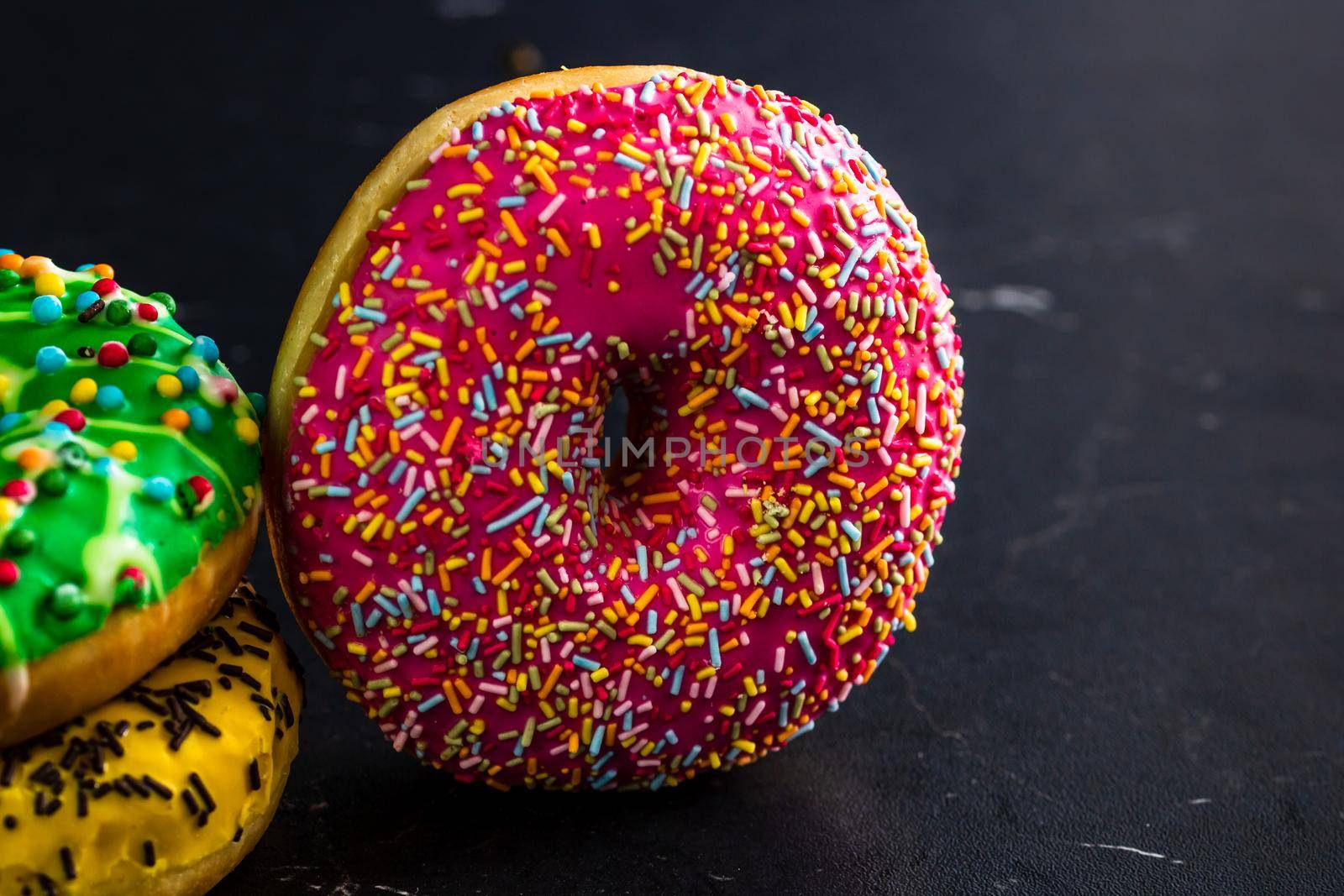 Glazed donuts with sprinkles isolated. Close up of colorful donuts.