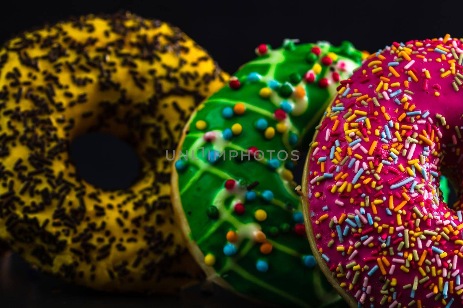 Glazed donuts with sprinkles isolated. Close up of colorful donuts.