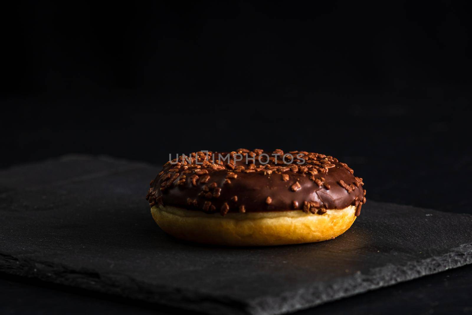 Chocolate glazed donut with chocolate chips isolated. Close up of delicious donut.