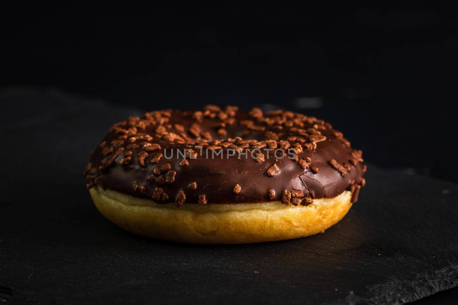 Chocolate glazed donut with chocolate chips isolated. Close up of delicious donut.