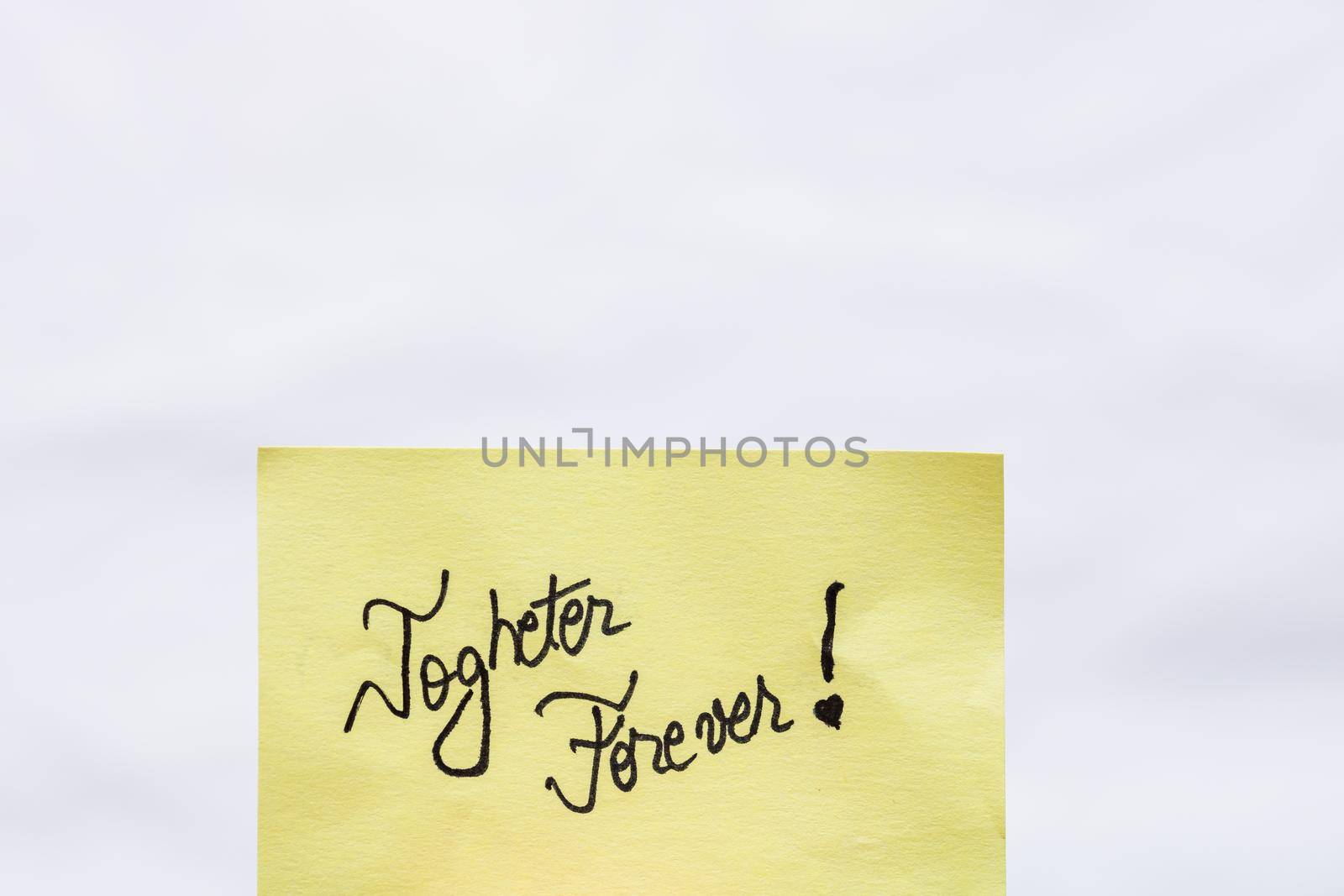 Togheter forever handwriting text close up isolated on yellow paper with copy space.