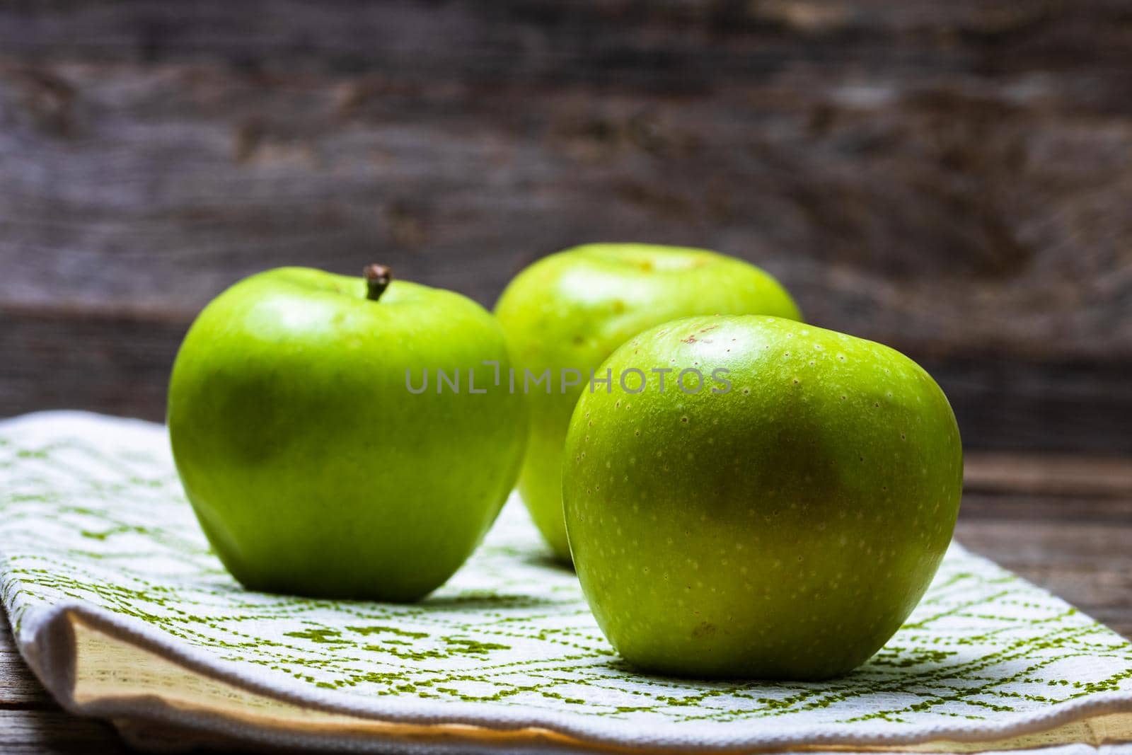 Detail on ripe green apples on wooden table. by vladispas