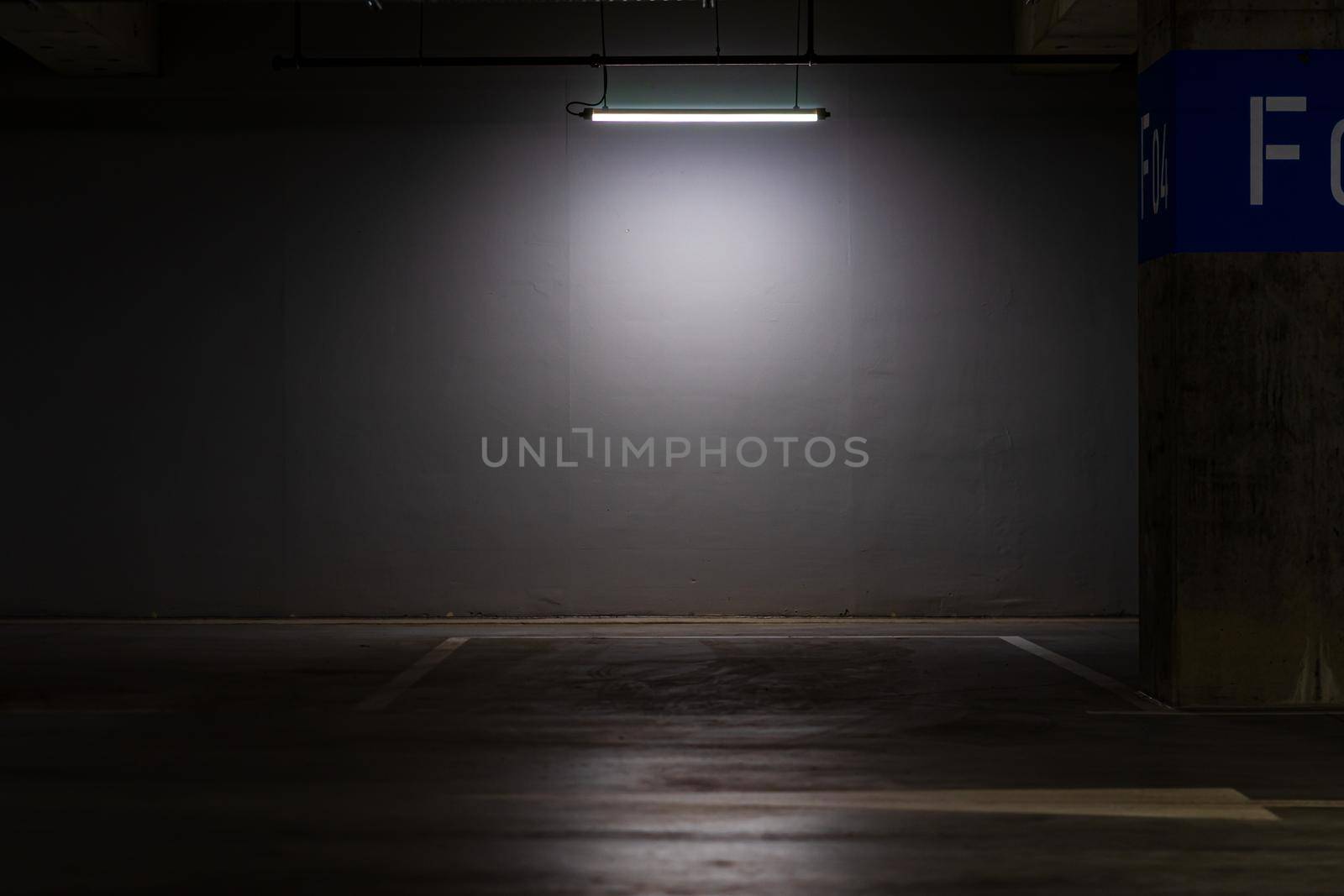 Empty parking lot with overhead dim light, underground parking garage.