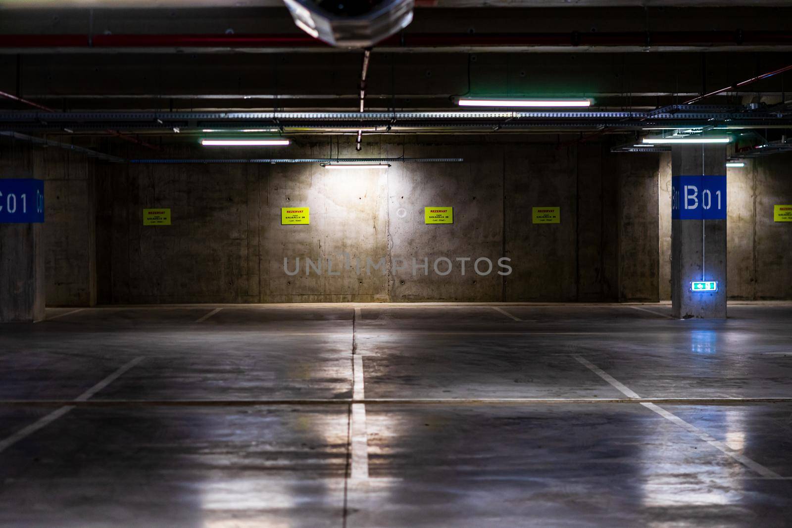 Empty parking lot with overhead dim light, underground parking garage.