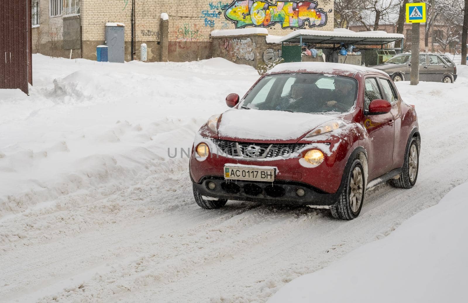 Lutsk, Ukraine - February 12,2020: Stuck car in snow and ice. City street after blizzard. Buried vehicle in snowdrift. Parking in winter after snowfall. Uncleaned road. Record-breaking amounts of snow