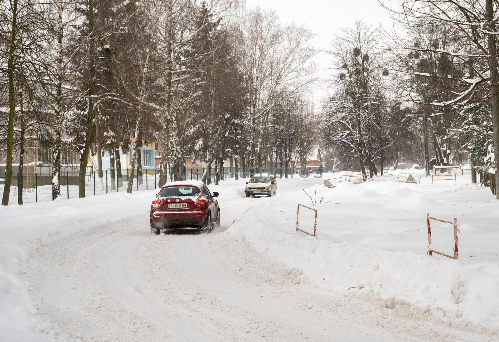 Lutsk, Ukraine - February 12,2020: Stuck car in snow and ice. City street after blizzard. Buried vehicle in snowdrift. Parking in winter after snowfall. Uncleaned road. Record-breaking amounts of snow