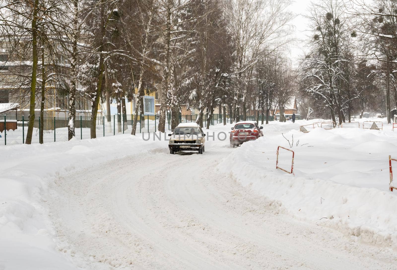 Lutsk, Ukraine - February 12,2020: People on street after snow storm. City street after blizzard. Record-breaking amounts of snow. Uncleaned slippery roads and sidewalk in winter. Cars in snowdrift