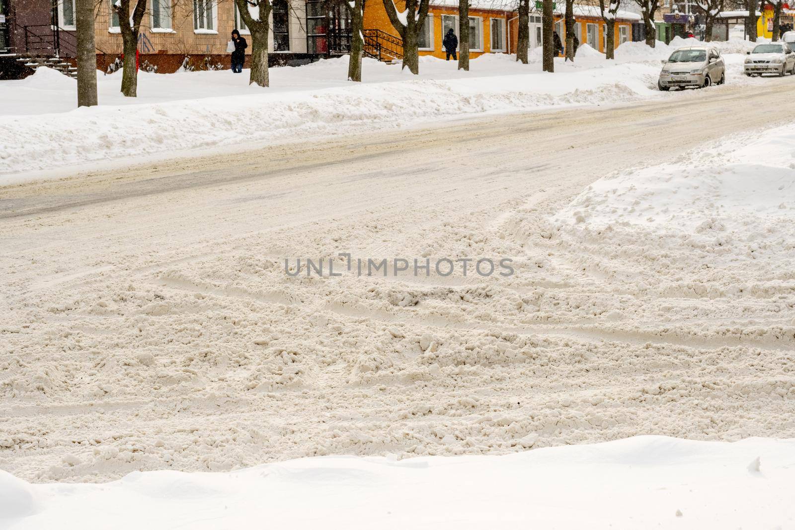 Lutsk, Ukraine - February 12,2020: Uncleaned slippery roads and sidewalk in winter. Cars in snowdrift. People on street after snow storm. City street after blizzard. Record-breaking amounts of snow