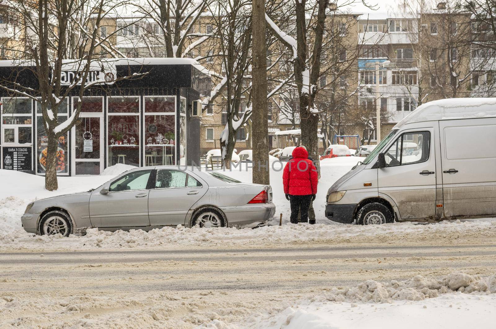 Lutsk, Ukraine - February 12,2020: Stuck car in snow and ice. City street after blizzard. Buried vehicle in snowdrift. Parking in winter after snowfall. Uncleaned road. Record-breaking amounts of snow