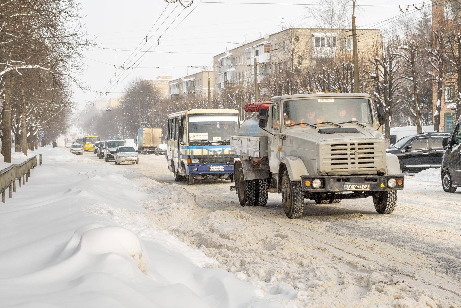 Lutsk, Ukraine - February 12,2020: Stuck car in snow and ice. City street after blizzard. Buried vehicle in snowdrift. Parking in winter after snowfall. Uncleaned road. Record-breaking amounts of snow
