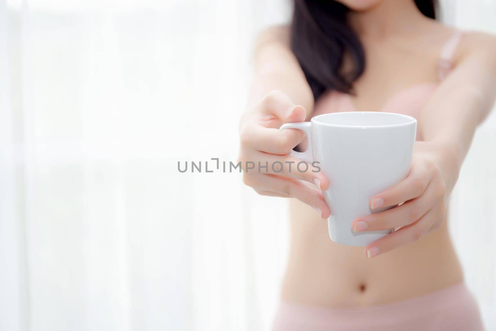 Closeup young asian sexy woman in underwear giving coffee near windows in the morning, girl with seductive figure fit serving beverage is breakfast for relax after wake up, lifestyle concept.