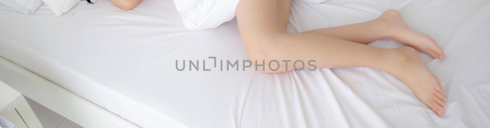 Beautiful leg of woman slim sexy on bed at bedroom, skin smooth of beauty girl feet health care, comfort and wellbeing, female lying sleep for relax with blanket, lifestyle concept, banner website.