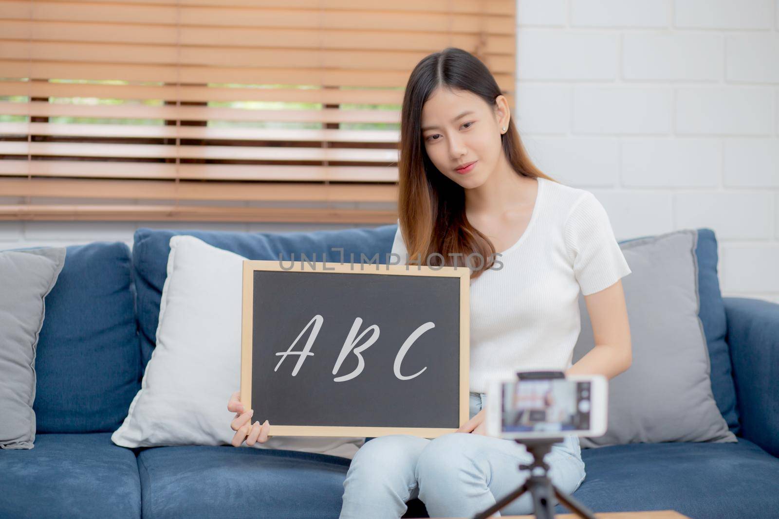Young asian woman is teacher teaching language english with student for e-learning online at home, girl working and talking lesson in class with smartphone, stay home, new normal, education concept.