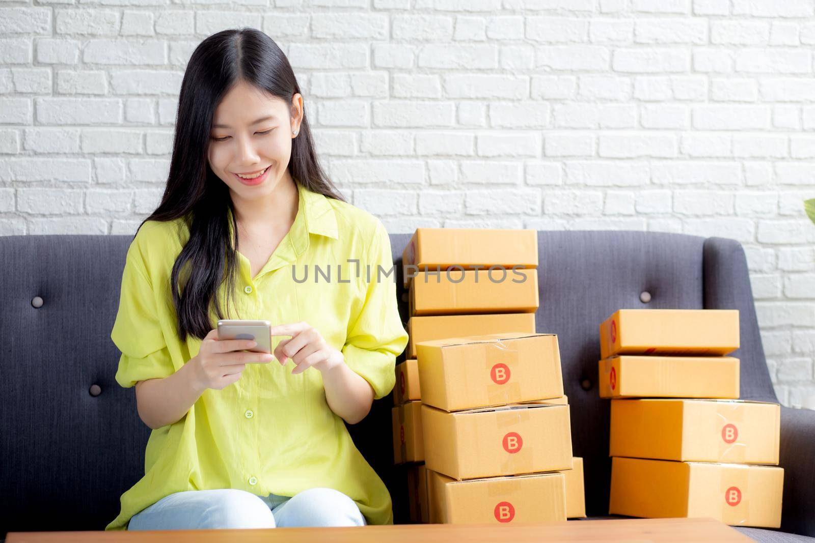 Young asian woman is entrepreneur check order from smartphone with customer while purchase online, logistic and delivery, online shopping, female is seller of business SME, merchant looking phone.