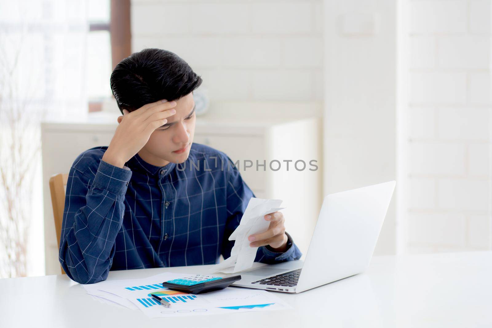 Young asian man calculating expenses household about finance and frustrated on desk at home, male checking bill having stress and worried, debt and tax, expression and emotion, business concept.