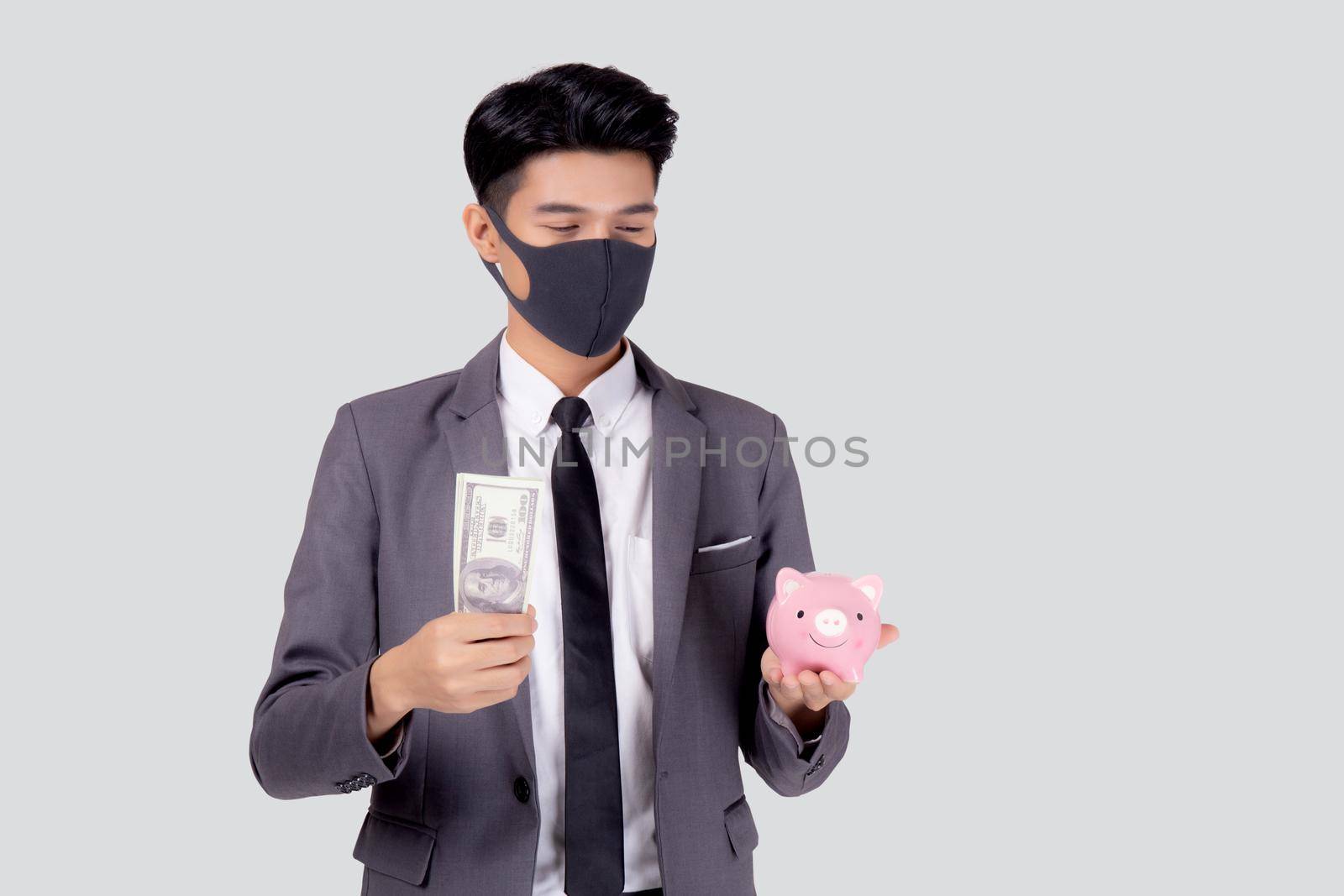 Young asian businessman in face mask holding money dollar and piggy bank isolated on white background, crisis of economic, business man in mask investment finance and saving during disease covid-19.