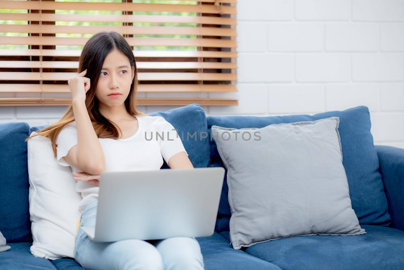 Young asian woman work on laptop computer on sofa at home with frustrated and bored, freelance girl unhappy and tired with unsuccessful, upset from problem, failure and mistake, business concept.