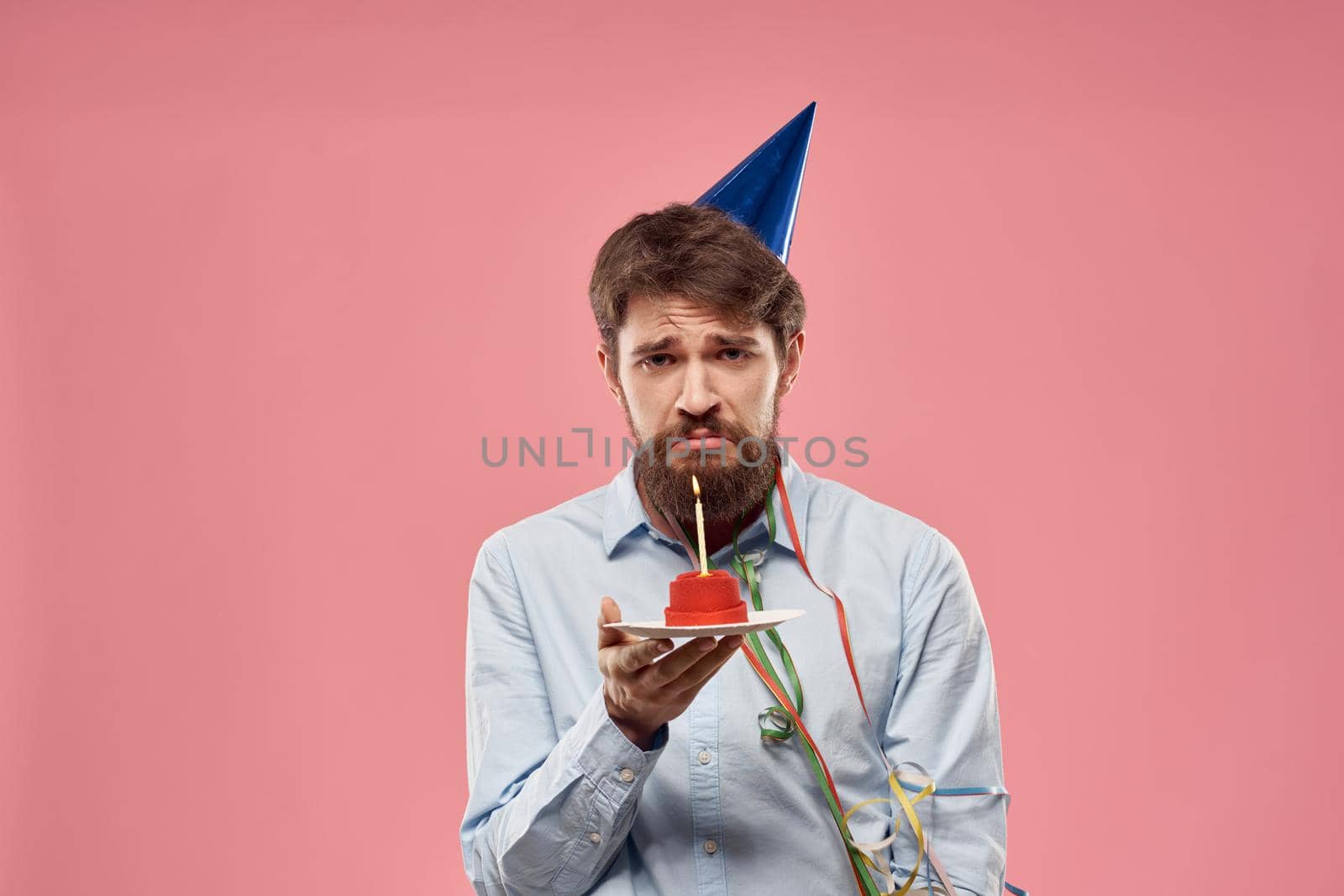 Birthday of a man with a cake and with a candle on a pink background. High quality photo