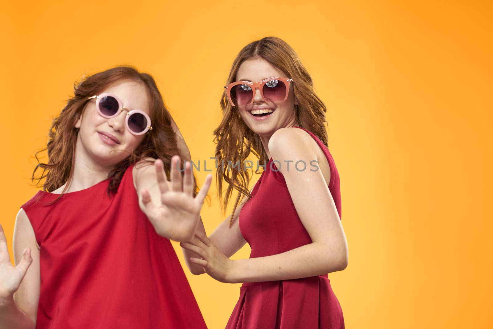 Two sisters and fun sunglasses fashion Friendship yellow background family. High quality photo