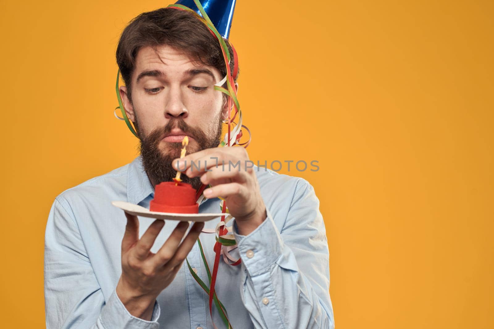 Guy with a cake in a plate on a yellow background holidays candle cropped view. High quality photo