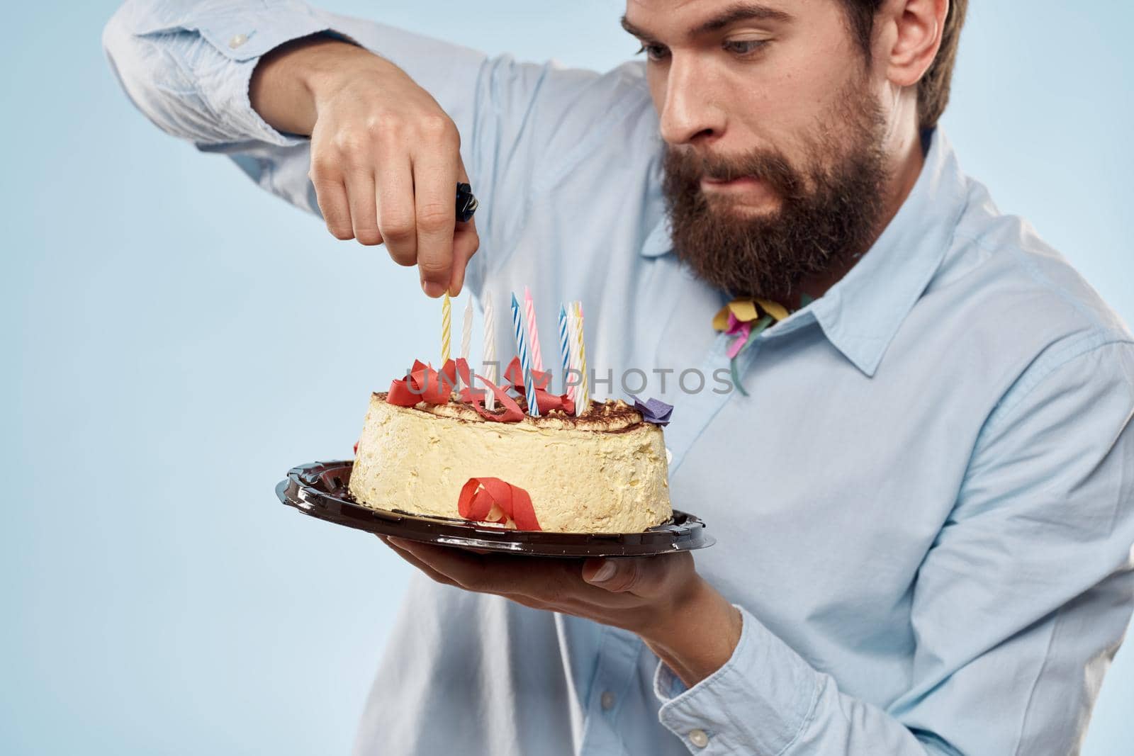 Man with a plate of cake and a festive candle blue background cap corporate party. High quality photo