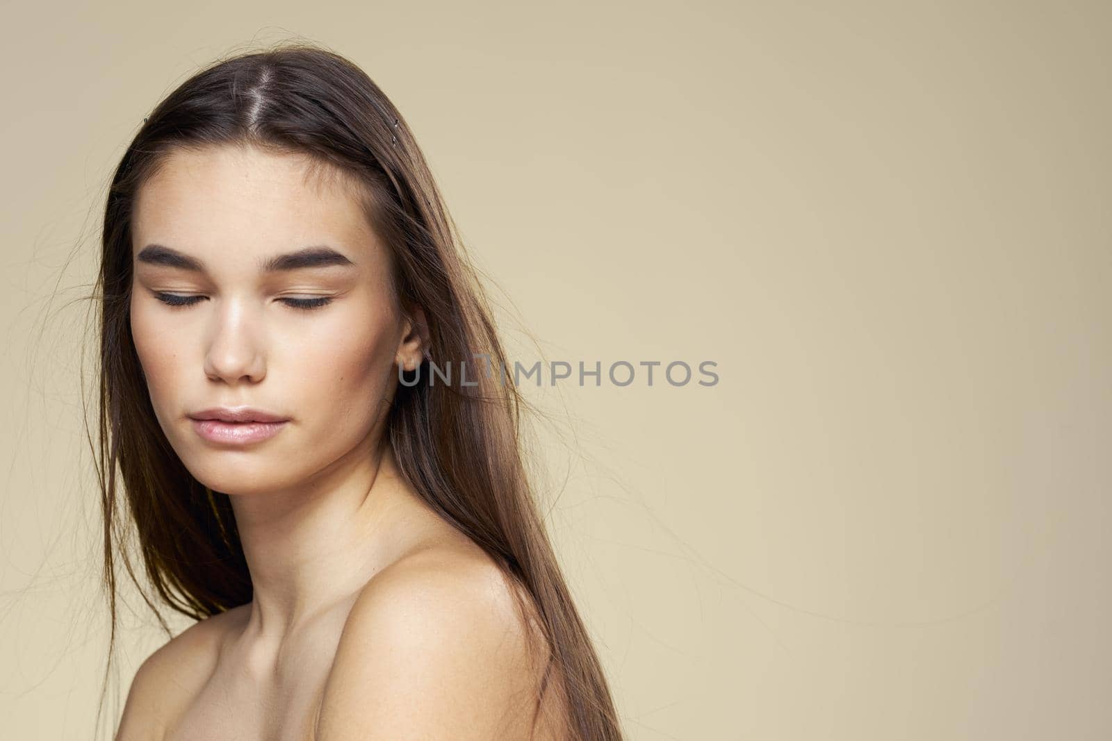 Pretty woman naked shoulders long hair body care beige background. High quality photo