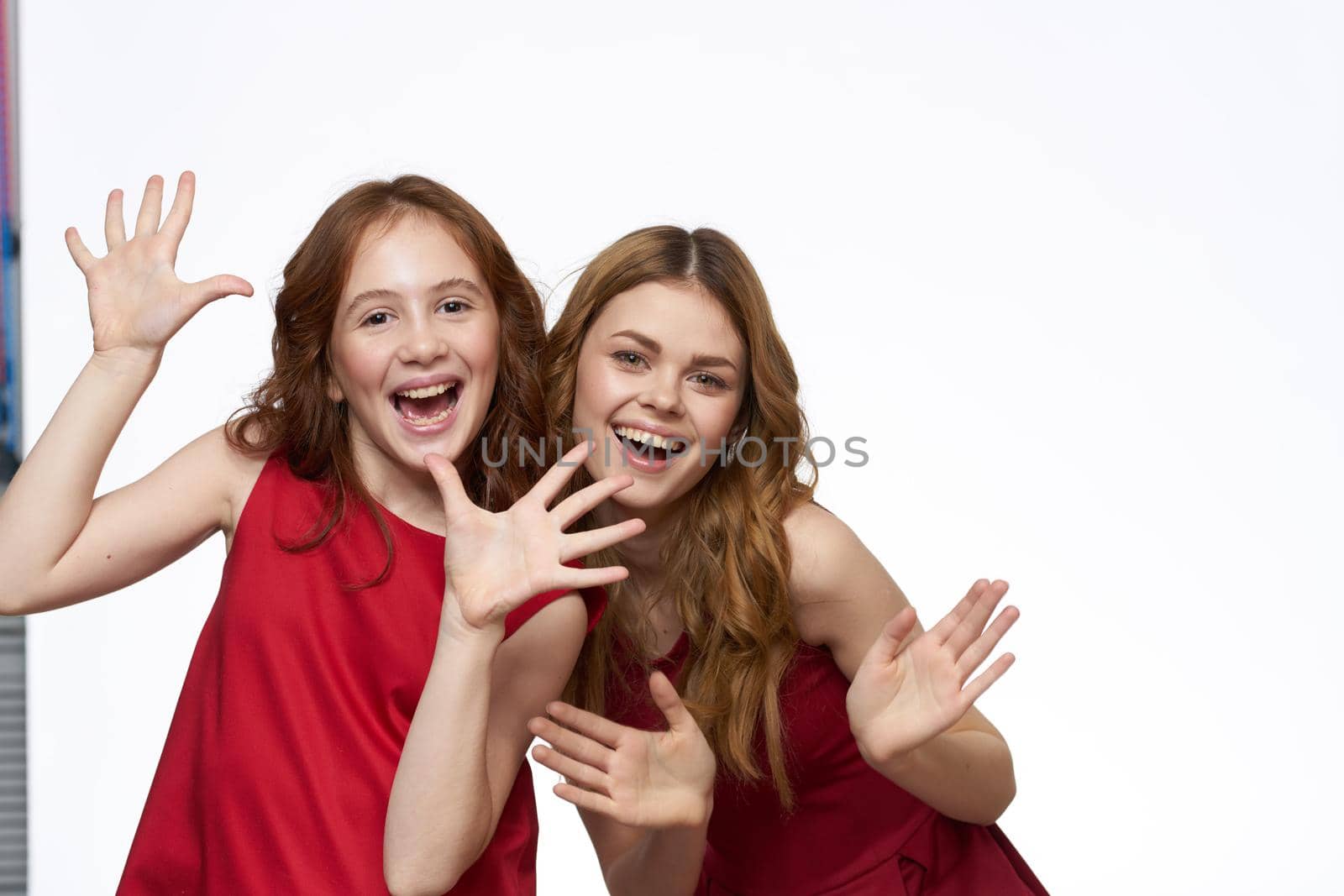 Cheerful mom and daughter next to red dresses hugs lifestyle light background smile. High quality photo