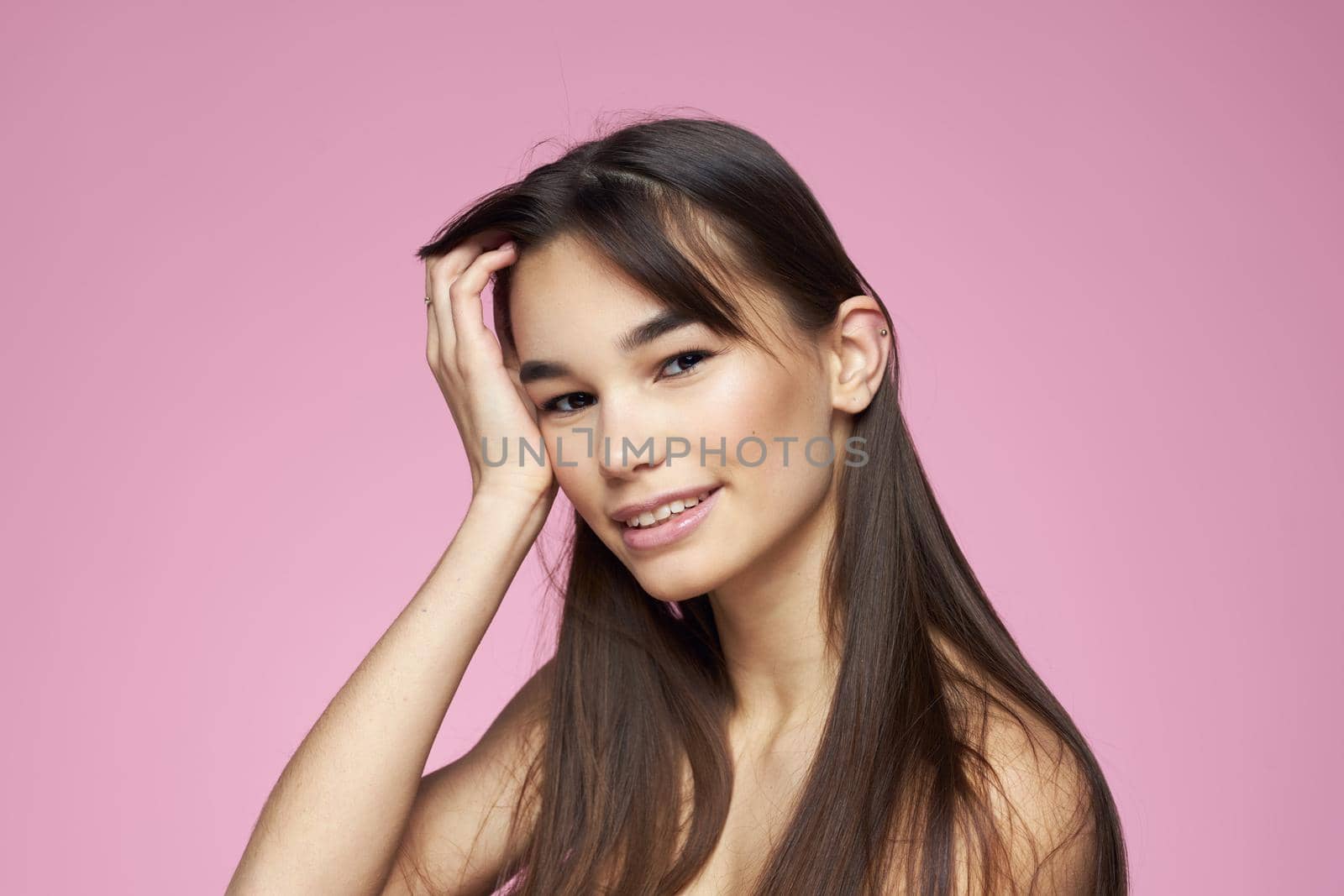 brunette bare shoulders clear skin body care pink background. High quality photo