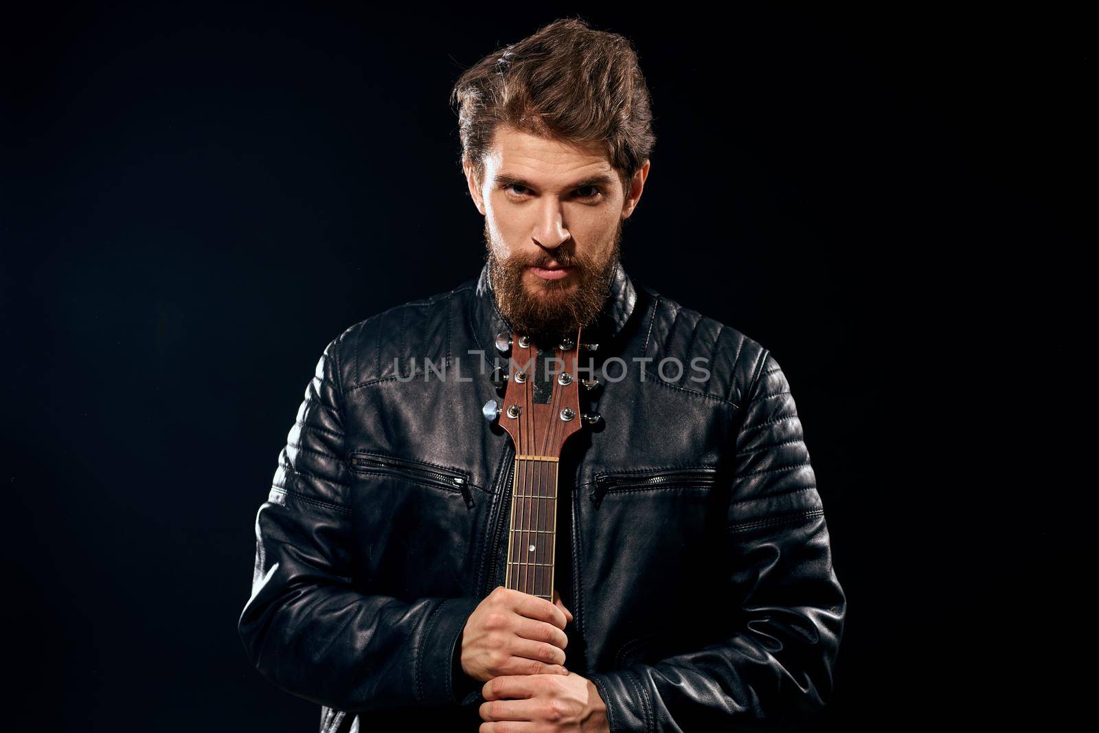 A man with a guitar in his hands leather jacket music performance rock star modern style dark background. High quality photo