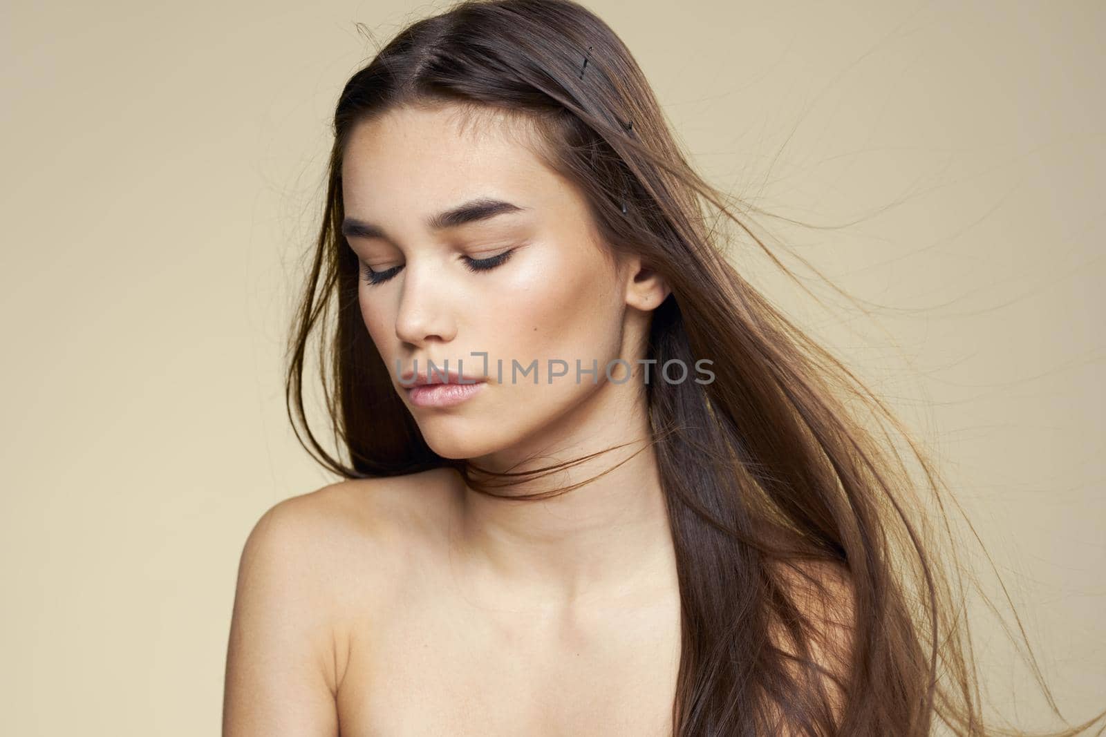 Pretty woman naked shoulders cosmetics clean skin hair care beige background. High quality photo