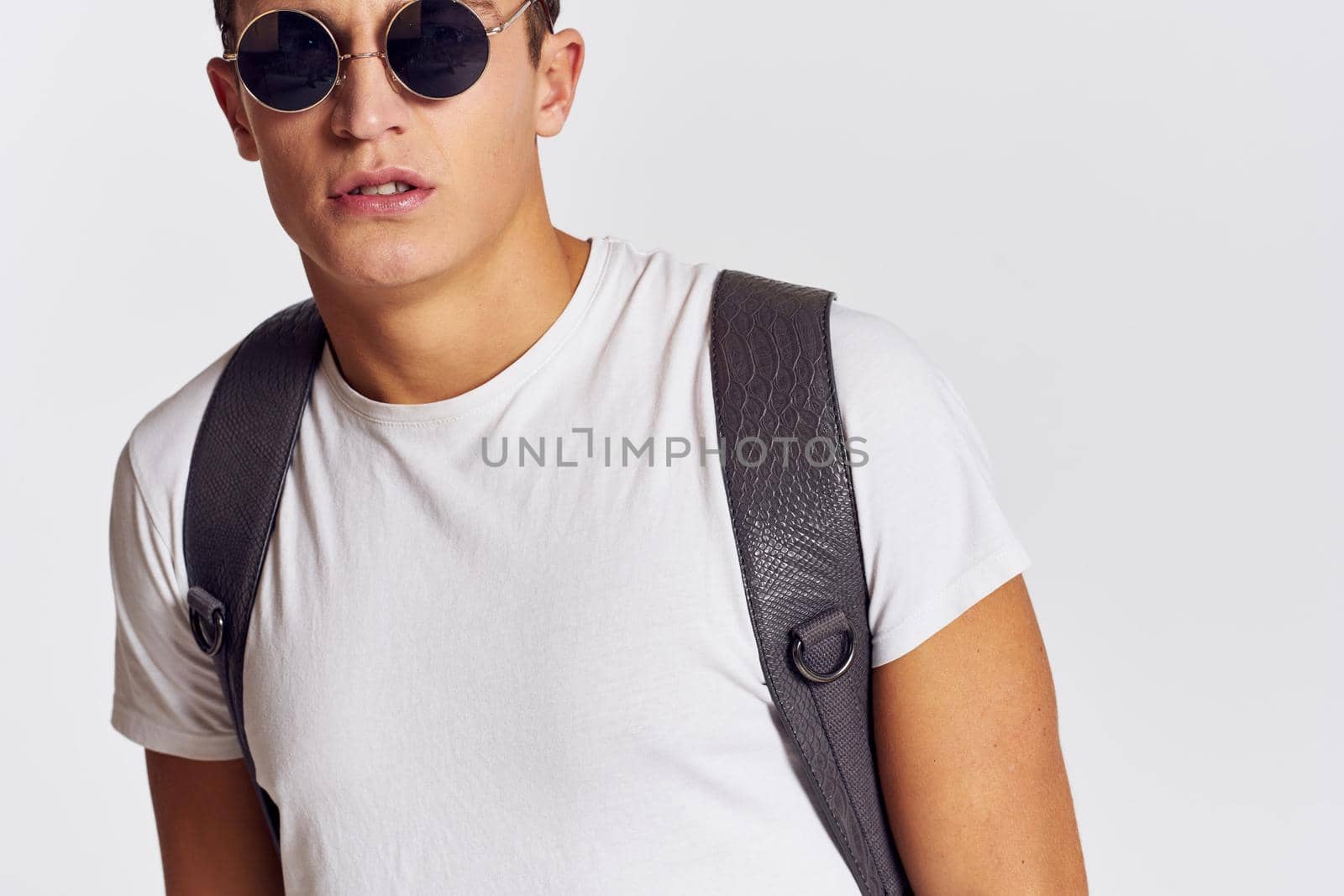 handsome man with backpack on his back gesturing with his hands in a t-shirt and wearing glasses Copy Space portrait cropped view