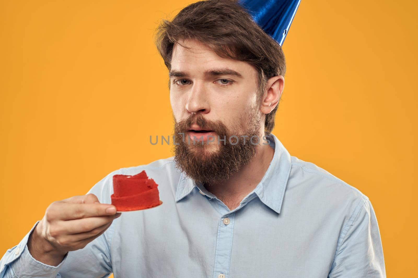 Man with cake on yellow background birthday party hat cropped view. High quality photo