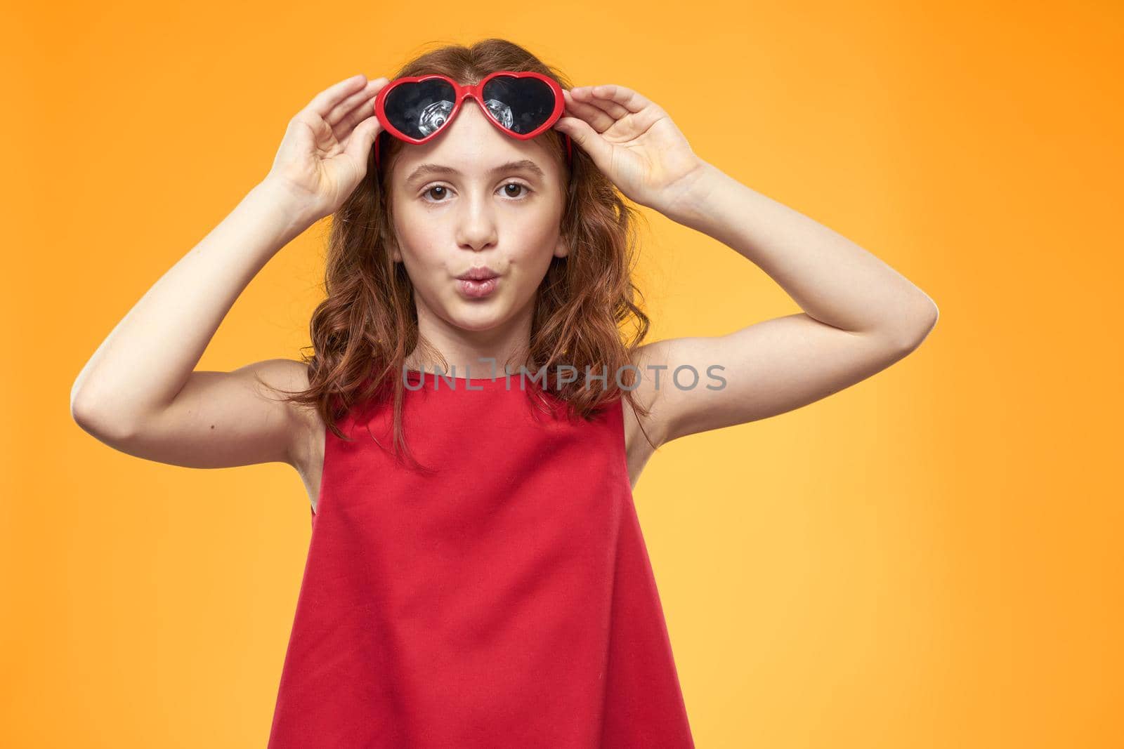 Cheerful little girl red dress curly hair yellow background childhood. High quality photo