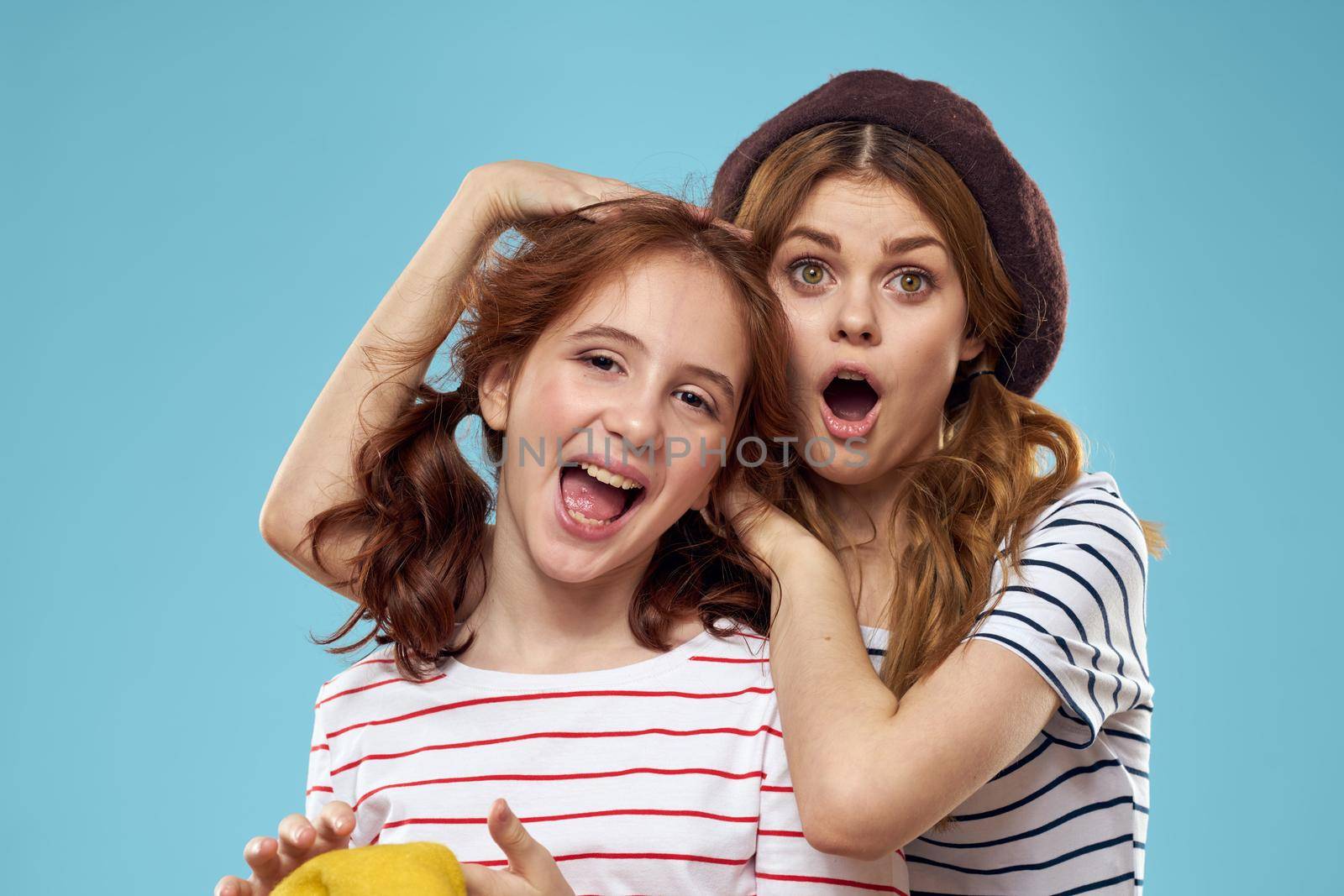 Fashion sisters in hats fun lifestyle blue background studio. High quality photo