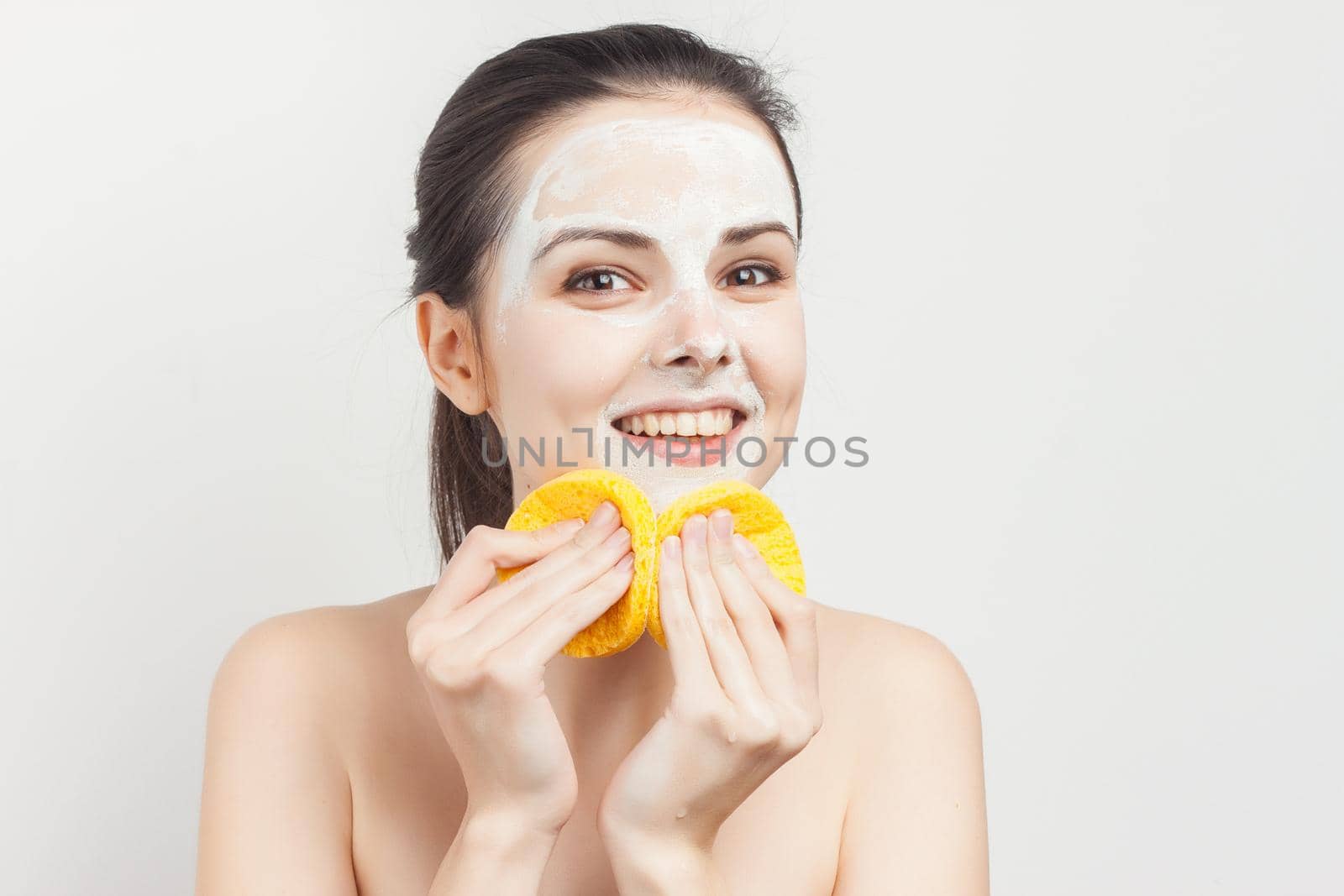 emotional woman with sponges in hands cream mask on face cropped view. High quality photo