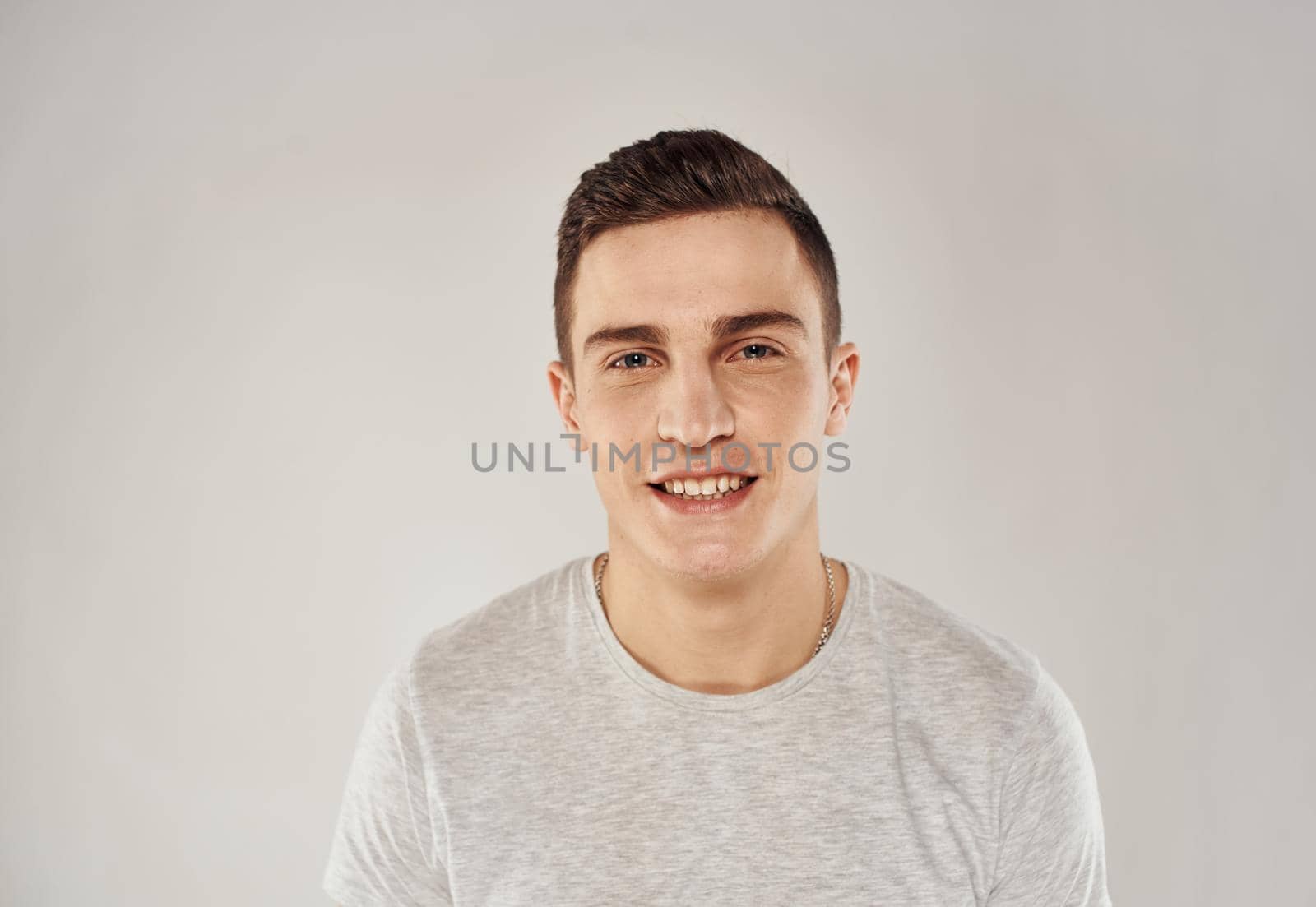Cheerful handsome man in a white T-shirt gray background. High quality photo