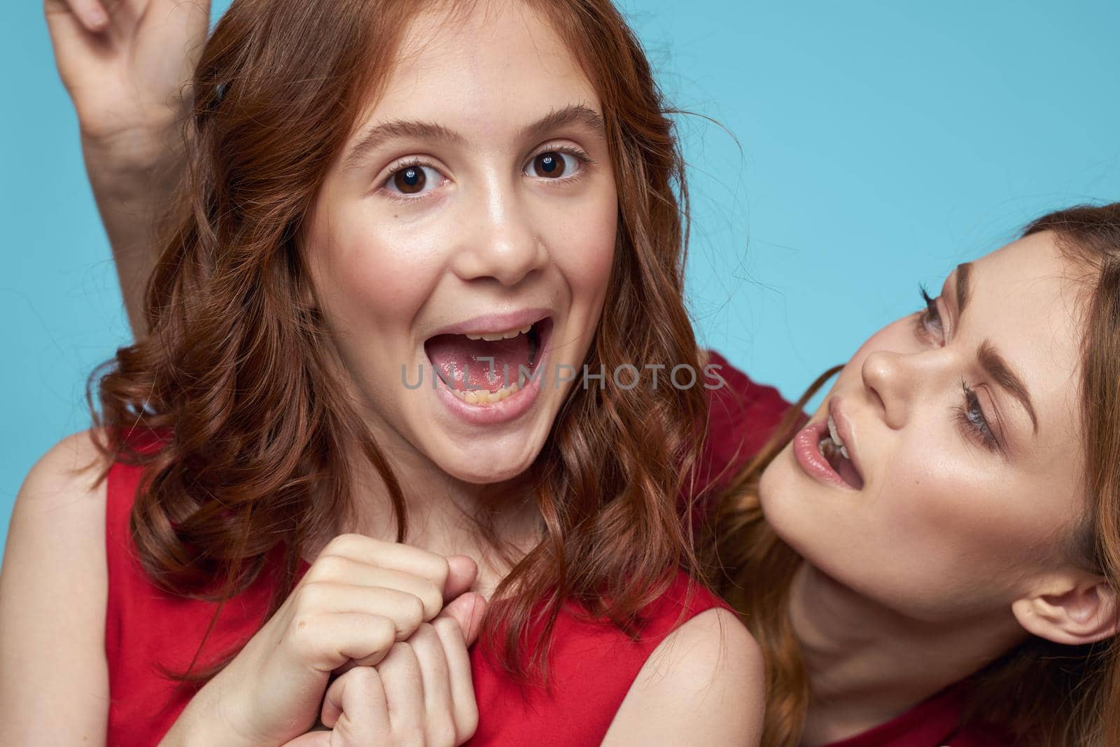 Cheerful mom and daughter hugs joy lifestyle communication friendship blue background. High quality photo