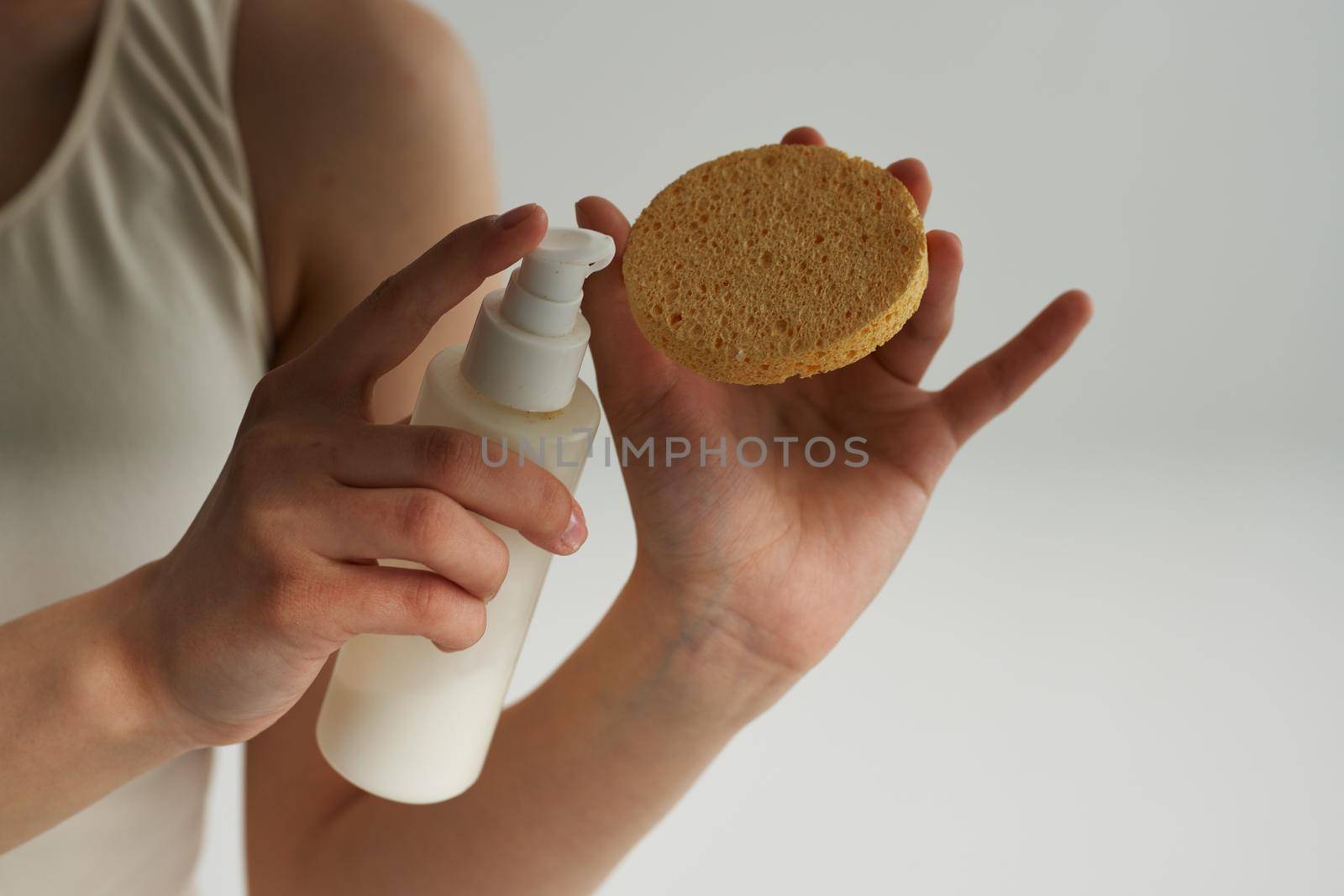 Woman in white t-shirt holds sponge with cream skin care close-up by SHOTPRIME