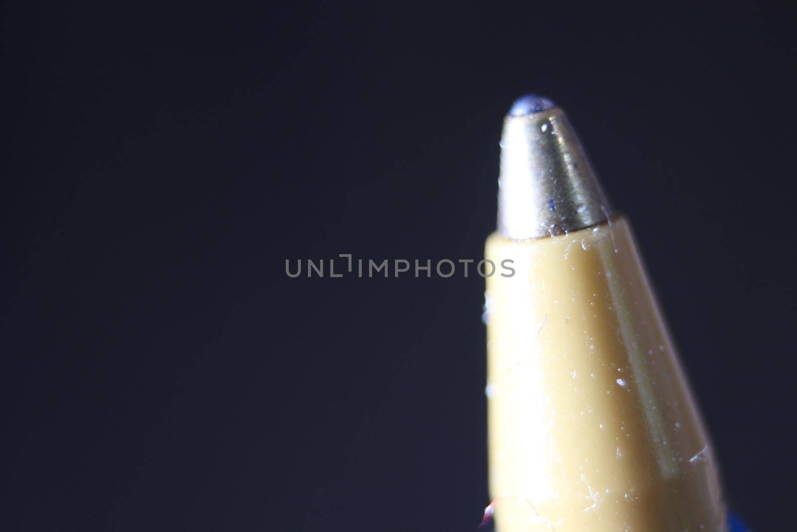 Macro photo of ballpoint pen tip with dark grey background. Extreme macro image of metal ballpoint pen on grey background.