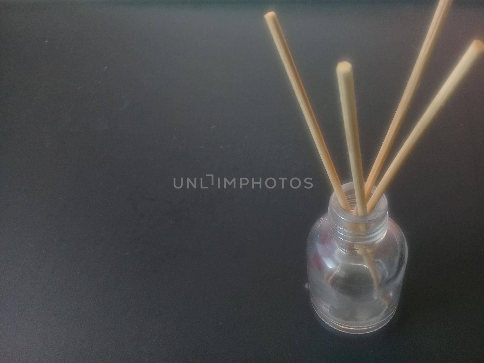 Close-Up Of Incense Sticks In glass Container Against Gray Background by Photochowk