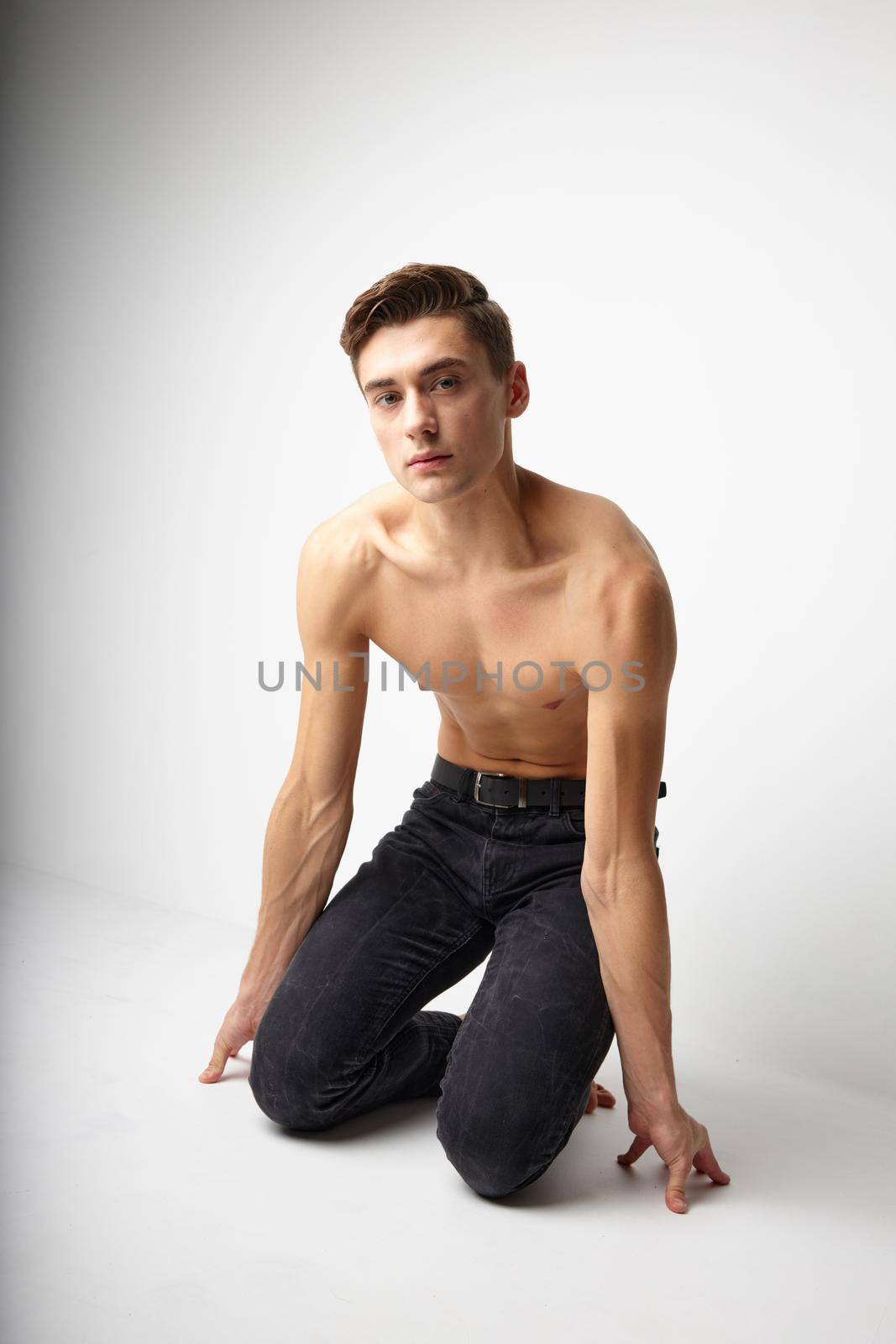 Man kneeling in black trousers nude torso posing lifestyle. High quality photo