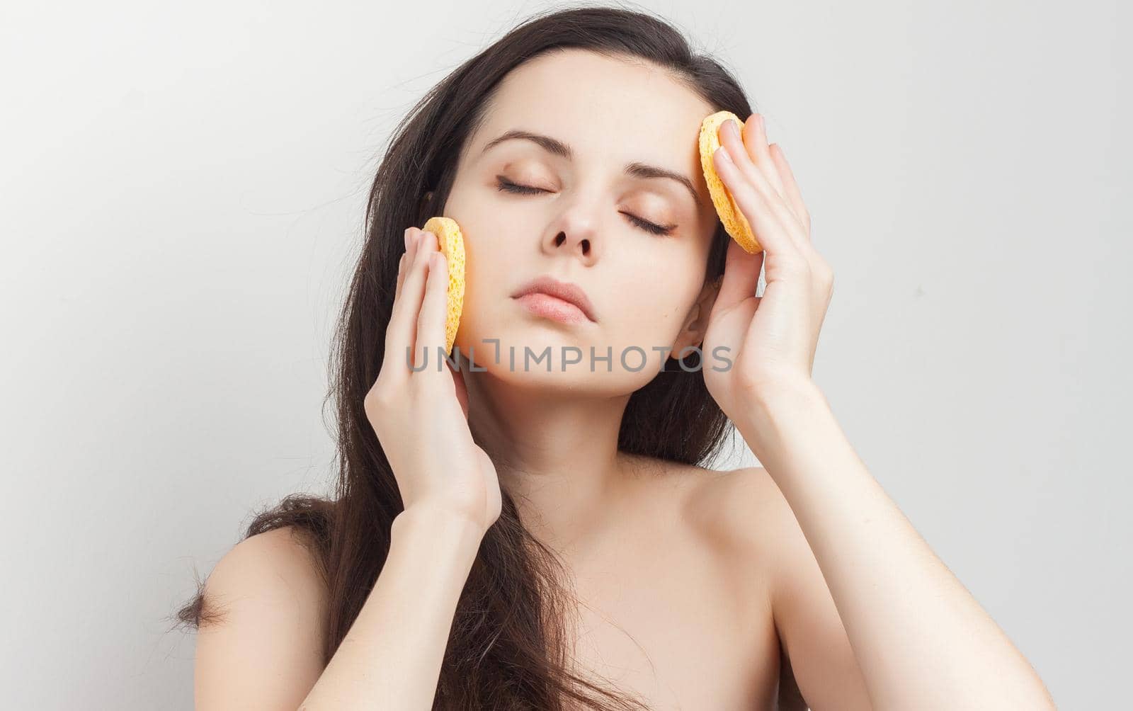 brunette with bare shoulders sponge in hand grooming. High quality photo