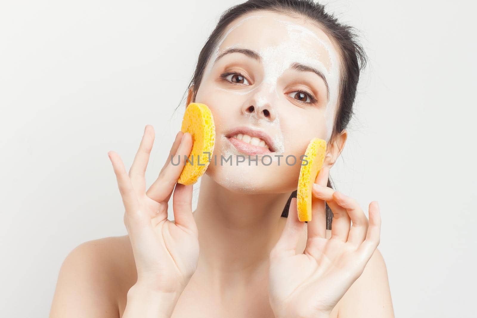 cute brunette with sponges in hands cream mask scrub rejuvenation. High quality photo